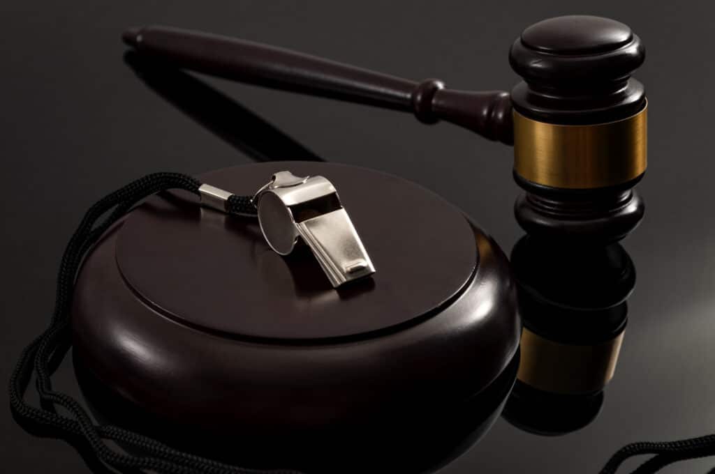 Whistleblower protection law and freedom of information legislation conceptual idea with metal whistle and wooden judge gavel on dark background