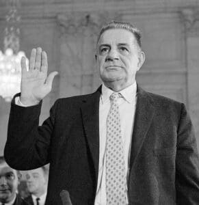 American Mobster Joseph Michael Valachi taking the oath before the US Senate with his right hand raised.